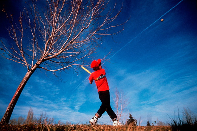 photo of boy in red shirt swinging a baseball bat